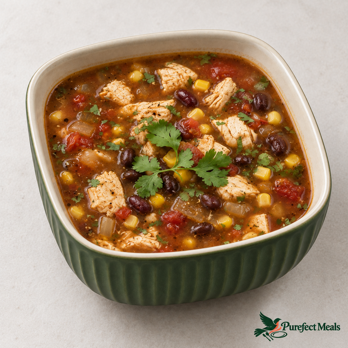 Chicken tortilla soup in a fluted forest-green ceramic bowl with an ivory interior on a white background