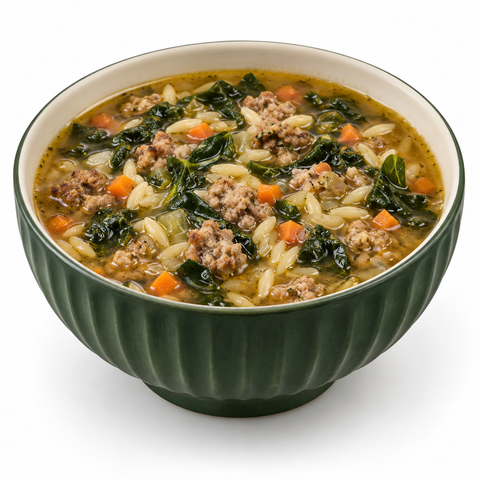 Italian sausage and orzo soup with kale and carrots in a fluted forest-green ceramic bowl on white